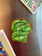 Load image into Gallery viewer, Needlepoint canvas stitched to look like avocado toast and finished as a fridge magnet
